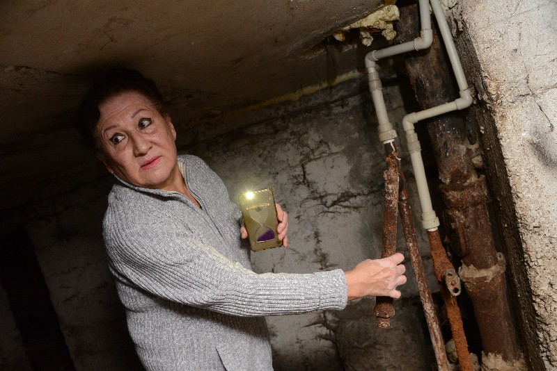 Нэля Масимова демонстрирует, как отваливаются в подвале трубы, если к ним прикоснуться.