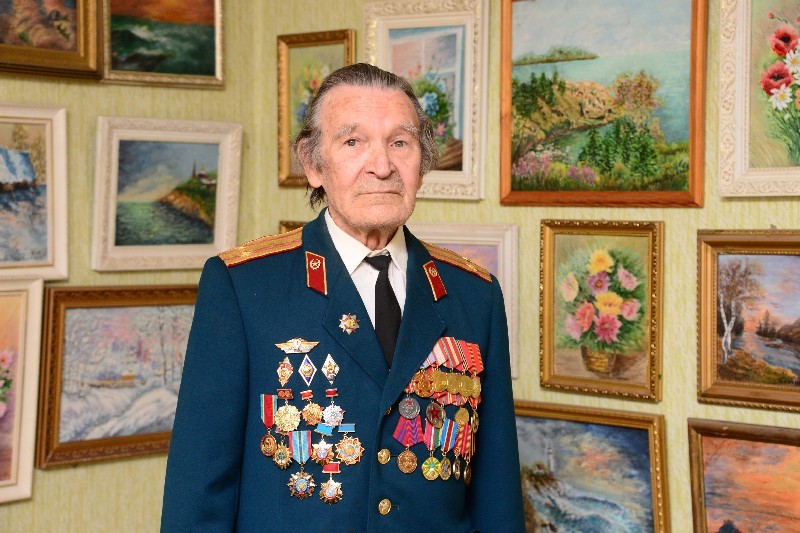 Владимир Гопчак на фоне картин, которые рисует его жена Вероника Ниловна после выхода на пенсию.