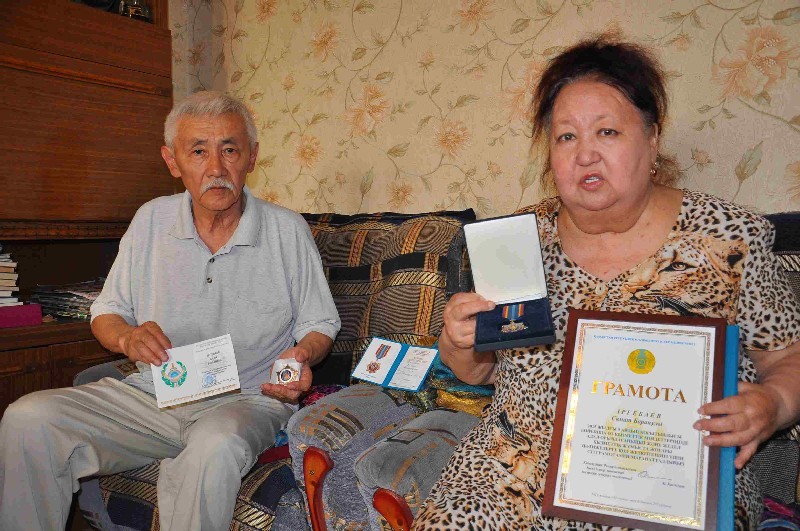 Родители Боран ИРГЕБАЕВ и Гульжамал ТУЛЕВЛЕНОВА показывают награды сына.